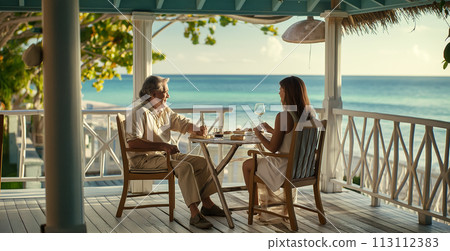 Siesta, beautiful adult people during lunch in a cafe on the ocean, enjoying a conversation and admiring the beautiful sunset in the sea, advertising a restaurant or cafe Siesta, beautiful adult people during lunch in a cafe on the ocean, enjoying a conversation and admiring the beautiful sunset in the sea, advertising a restaurant or cafe 113112383
