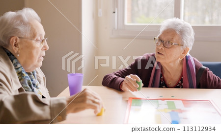 Women having fun playing Parcheesi board game in a geriatric Women having fun playing Parcheesi board game in a geriatric 113112934