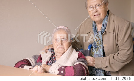 Senior women looking at camera together in a nursing home Senior women looking at camera together in a nursing home 113112936