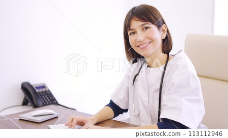 Female doctor using computer and smiling at camera Female doctor using computer and smiling at camera 113112946