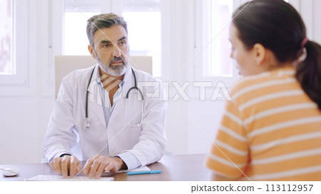 Doctor writing while talking with a patient in a clinic 113112957