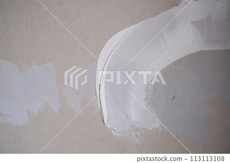 Applying decorative putty. White abstract texture of surface covered with putty. textured background of filler paste applied with putty knife in irregular dashes and strokes. Rough surface plaster Applying decorative putty. White abstract texture of surface covered with putty. textured background of filler paste applied with putty knife in irregular dashes and strokes. Rough surface plaster 113113108