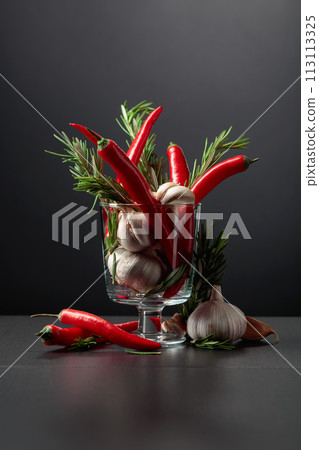 Red hot chili peppers, garlic, and rosemary on a black background. 113113325
