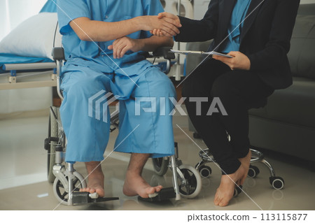Midsection of female nurse checking blood pressure of woman sitting on wheelchair in clinic 113115877
