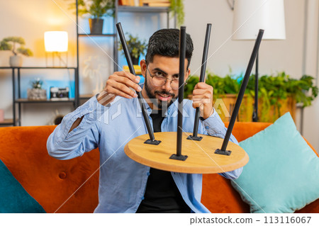 Happy Indian man finishing assembling furniture table desk collect repair fixing at home apartment 113116067
