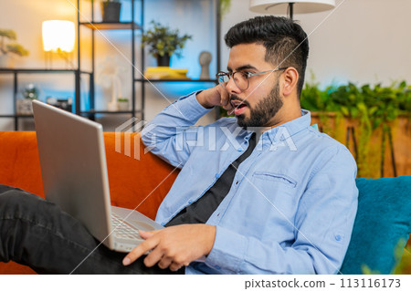 Happy Indian man using laptop receive good news shocked by victory celebrate lottery jackpot victory 113116173