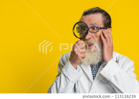 Senior doctor man holds magnifying glass near face looking at camera with big zoomed eye, analyzing 113116239