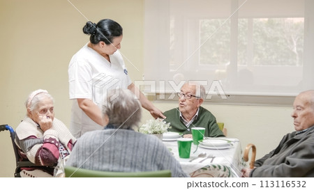 Caregiver talking to senior man in canteen at nursing home 113116532