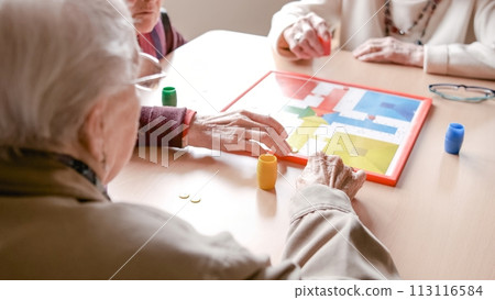 Senior friends playing ludo board game in nursing home 113116584