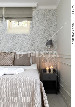 A bedroom with bed, nightstand, lamp, and candles in a house 113116758
