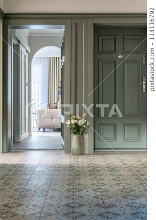 House hallway with a green door and floral vase fixture on wood flooring 113116792