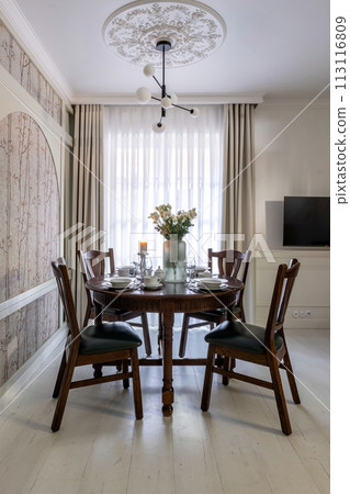 House interior with wooden table, chairs, vase of flowers, and stylish flooring 113116809