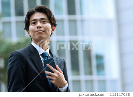 Businessman with a smartphone in the office district 113117028