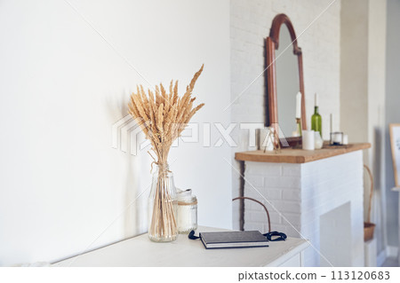Interior design with beautiful bouquet of dried pampas grass flowers, fireplace, mirrow, white wall, candle, notebook. Background with copy space, empty. Template, mockup for your design, poster, art. Interior design with beautiful bouquet of dried pampas grass flowers, fireplace, mirrow, white wall, candle, notebook. Background with copy space, empty. Template, mockup for your design, poster, art. 113120683