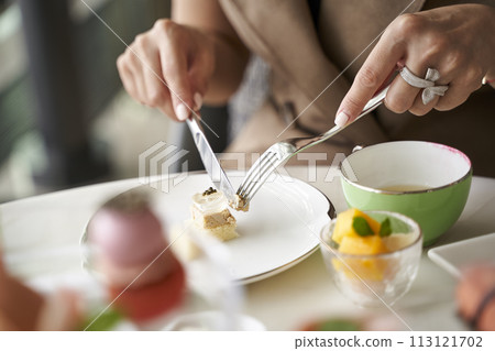 woman eating dessert using fork and knife in restaurant 113121702