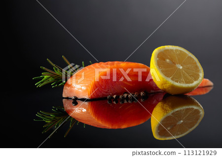 Smocked salmon with rosemary, lemon, and peppercorn on a black background. 113121929