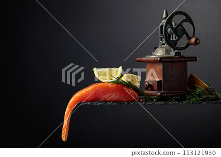 Salmon with rosemary, lemon, and peppercorn on a dark background. 113121930