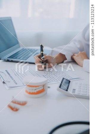 Dentists are discussing dental problems at report x-ray image on laptop screen to patients. Dentists are discussing dental problems at report x-ray image on laptop screen to patients. 113123214