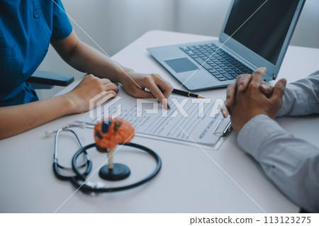 Doctor explaining brain functions to patient on model in office. 113123275