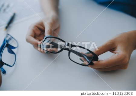 Close-up of Asian female doctor talking with elderly patient showing eyeball model and explaining eye disease in hospital 113123308