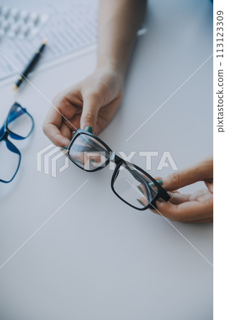 Close-up of Asian female doctor talking with elderly patient showing eyeball model and explaining eye disease in hospital 113123309
