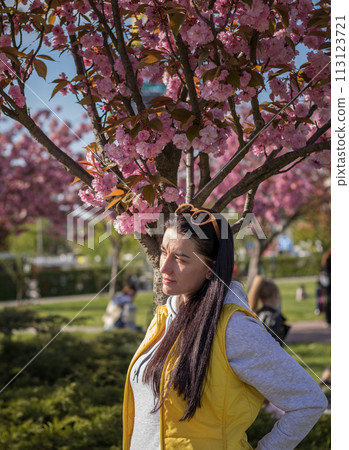 A happy mother and child are walking under the branches of a cherry tree 113123721