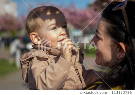 A happy mother and child are walking under the branches of a cherry tree 113123726