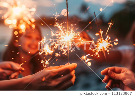 People enjoying sparklers during a festive evening gathering. People enjoying sparklers during a festive evening gathering. 113123907