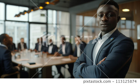 African male businessman stands in front of a conference table and poses with confidence in the office. 113125874