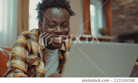 African American man in casual clothes playing on laptop in living room. 113126198