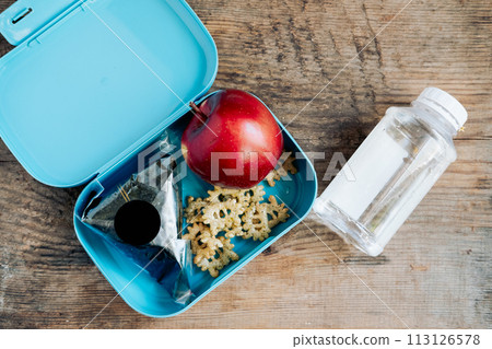 Asian student's lunchbox of onigiri,chips and apple with bottle of water,On wooden background Asian student's lunchbox of onigiri,chips and apple with bottle of water,On wooden background 113126578