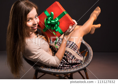 Sensual sexy attractive girl sits on a chair with gift in her hands 113127832