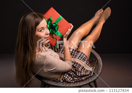 Sensual sexy attractive girl sits on a chair with gift in her hands Sensual sexy attractive girl sits on a chair with gift in her hands 113127834