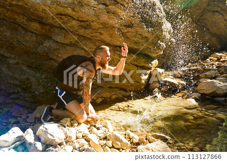 Hiker drinking water from the river. Man enjoys clean fresh unpolluted water in the mountain creek Hiker drinking water from the river. Man enjoys clean fresh unpolluted water in the mountain creek 113127866