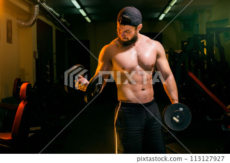 man in gym training with dumbbells 113127927