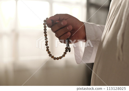 Closeup of unrecognizable Muslim man holding misbaha beads in hand, copy space 113128025