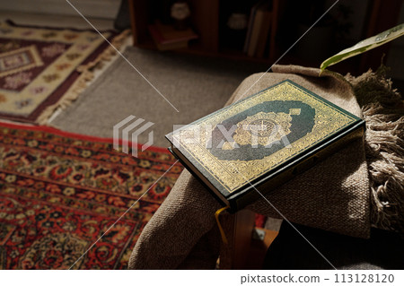 No people high angle of holy Quran book in green hard cover decorated with gold ornaments lying in living room No people high angle of holy Quran book in green hard cover decorated with gold ornaments lying in living room 113128120