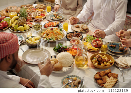 High angle vie of unrecognizable Muslim family sitting at abundant festive table celebrating Eid Al-Fitr, copy space High angle vie of unrecognizable Muslim family sitting at abundant festive table celebrating Eid Al-Fitr, copy space 113128189