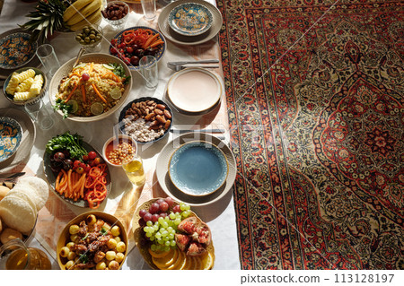 From above view no people shot of abundant festive table served for Uraza Bayram celebration in majilis with oriental carpet on floor 113128197