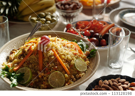 Selective focus closeup of pilaf decorated with slices of lime, carrot and grape on festive table prepared for Eid Al-Fitr celebration 113128198