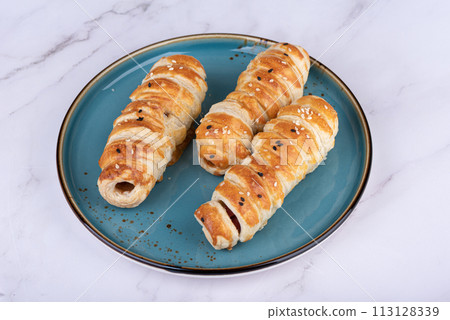 Three baked sausages in batter on a plate. 113128339