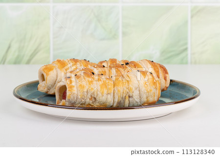 Close-up of baked sausages in batter on a plate. 113128340