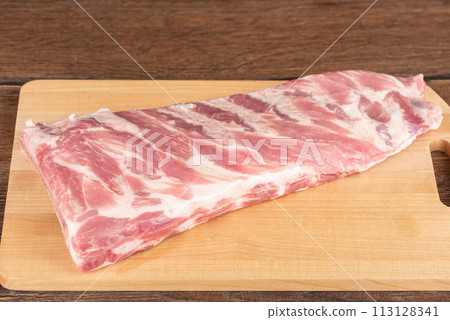 Raw pork ribs on a wooden cutting board. Raw pork ribs on a wooden cutting board. 113128341