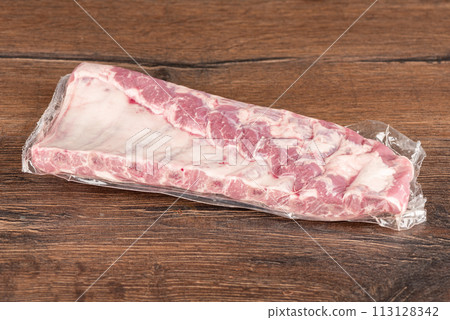 Vacuum-packed raw pork ribs on a tree background. Vacuum-packed raw pork ribs on a tree background. 113128342