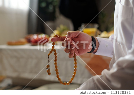 Closeup of hand of unrecognizable muslim man holding misbaha praying salah, copy space 113128381
