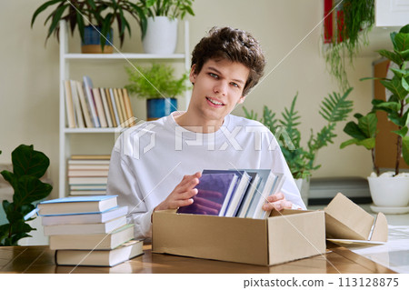 Satisfied young male customer unpacking cardboard box with online purchases, new books Satisfied young male customer unpacking cardboard box with online purchases, new books 113128875