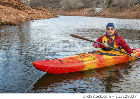 senior male paddler is paddling colorful river kayak on a calm lake - recreation concept, cold season on Horsetooth Reservoir in Colorado senior male paddler is paddling colorful river kayak on a calm lake - recreation concept, cold season on Horsetooth Reservoir in Colorado 113129327