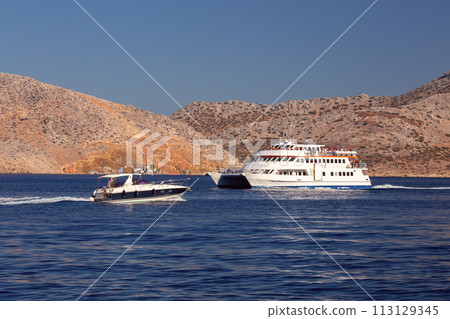 Tourist boats in a blue bay against the backdrop of mountains. Tourist boats in a blue bay against the backdrop of mountains. 113129345