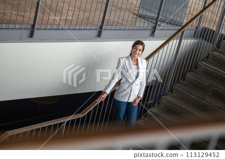 Woman in white jacket and jeans on the stairs in the office building Woman in white jacket and jeans on the stairs in the office building 113129452