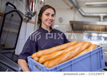 Employee holding baguettes at commercial bakery 113129477
